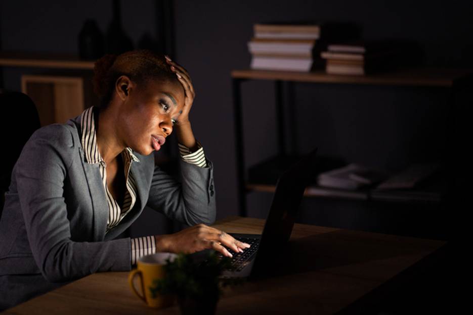 Woman stressed at work late at night - Overtime Violations